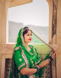 Portrait of smiling young woman standing against wall