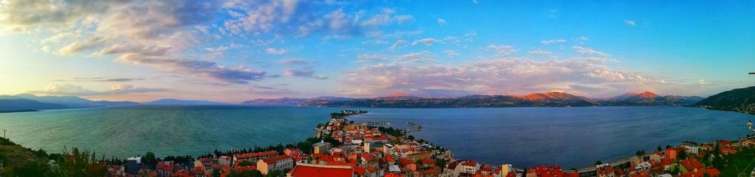 Panoramic shot of crowd by sea against sky