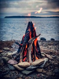 Campfire at beach against sky