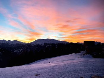 Scenic view of snow covered mountains against sky at sunset