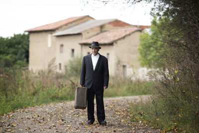 Emigrant with suitcase and vintage suit leaving his village to look for work  , old photography