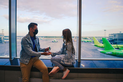 Young couple sitting on glass window