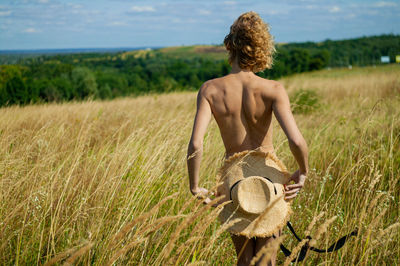 Rear view of naked woman standing on field