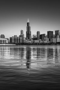 Sea and buildings in city against clear sky