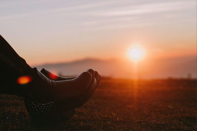 Low section of woman against sunset sky