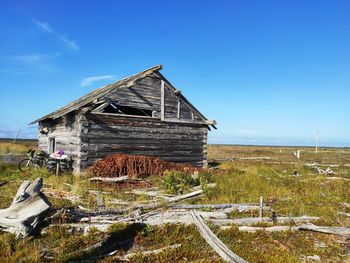 Abandoned building on field against blue sky