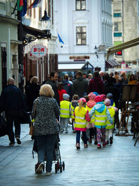 Rear view of people walking on city street