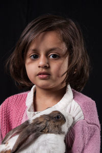 Close-up portrait of cute girl against black background