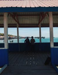 Rear view of people sitting on chair by sea against sky