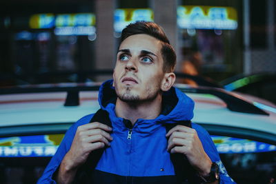 Young man in car against illuminated city at night