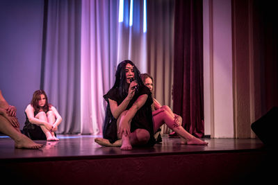 Young woman sitting with arms raised in music concert