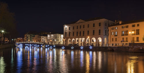 Treviso by night during christmas. university bridge and the light stars reflect on the river sile.