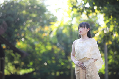 Young woman looking away while standing on tree
