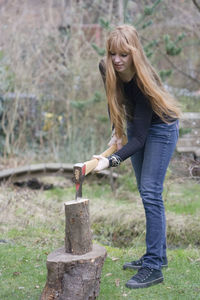 Portrait of young woman chopping wood