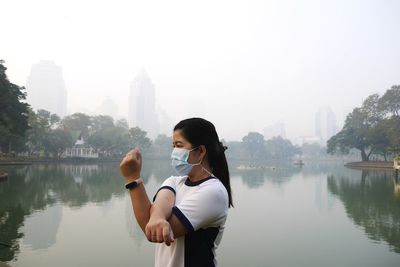 Woman standing by lake against sky