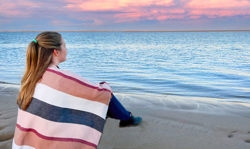 Blond woman sitting at ocean at chatham, cape cod