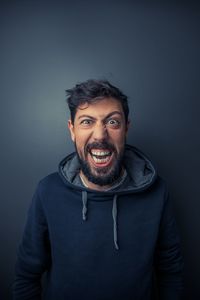 Portrait of angry man against gray background