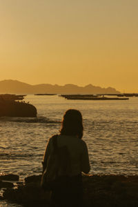 Rear view of silhouette people at beach against sky during sunset