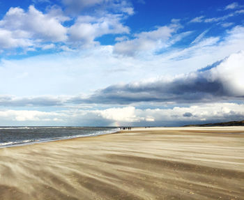 Scenic view of beach against cloudy sky