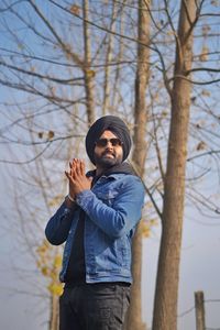 Young man wearing turban standing by bare trees