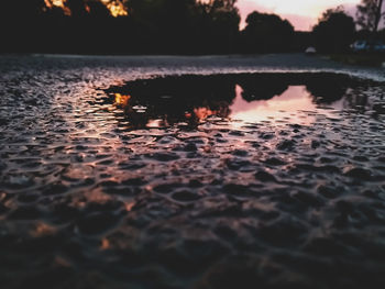 Surface level of lake against sky during sunset