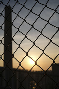 Full frame shot of chainlink fence against sky during sunset