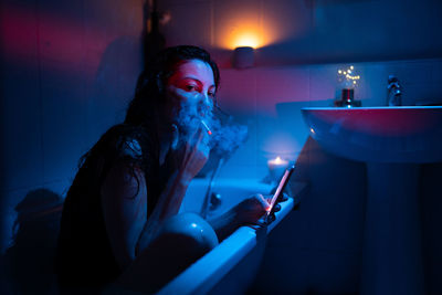 Sad drunk addicted woman sit alone in cold bath smoking. alcohol addiction problem and depression