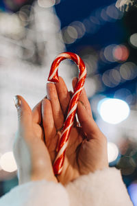 Christmas details. female hands holding red white cane sweet lollipop 