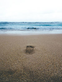 Footprints on sand at beach against sky