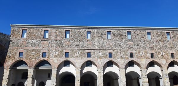 Low angle view of historic building against clear blue sky