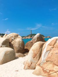 Rocks on beach against blue sky