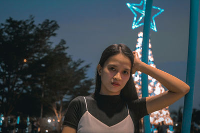 Portrait of young woman standing against trees