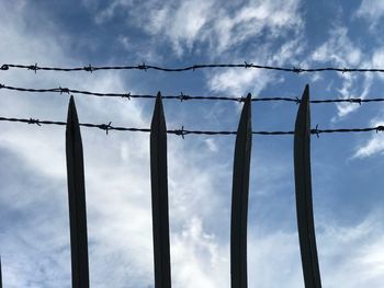 Low angle view of silhouette barbed wire against sky