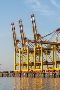 Cranes at commercial dock against sky