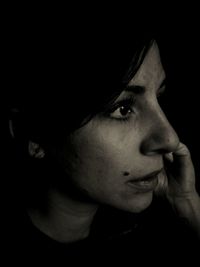 Close-up portrait of young woman against black background