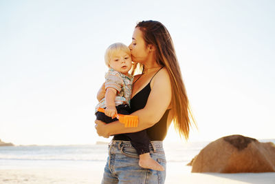 Mother and son at beach against sky