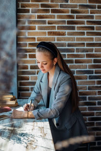 A young woman is sitting at a table and writing in a notebook.a business woman works as a freelancer