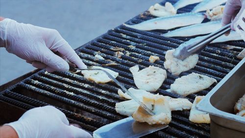 Close-up of person preparing food on barbecue grill