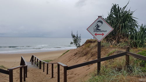 Information sign on beach against sky