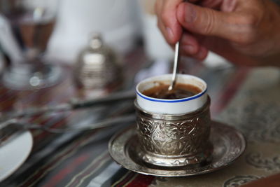 Close-up of hand pouring tea in cup on table