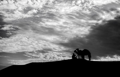 Silhouette men on land against sky