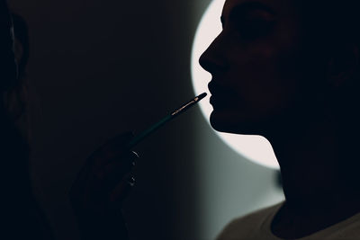 Close-up of man holding syringe against black background