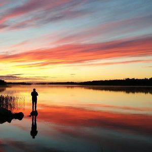 Silhouette man standing on beach against sky during sunset