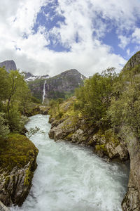 Scenic view of waterfall amidst trees against sky
