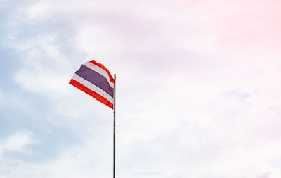 The thai flag was blown by the wind, fluttering on the pole. the flag consists of red, blue , white.