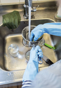 Cropped image of woman washing sauce pan at sink in kitchen