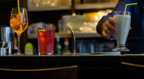 Close-up of cocktail glasses on a bar counter served by a bartender