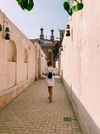 Rear view of woman on footpath amidst buildings