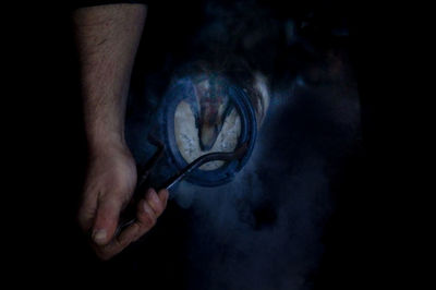 Cropped hand of farrier putting shoe on horse leg in stable