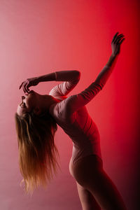 Midsection of woman with arms raised against red background